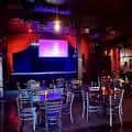 Interior del salón principal con mesas dispuestas para evento y pantalla en el fondo
