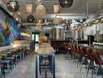 Interior del Monolith Brewing con tanques de fermentación y barra de servicio