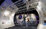 Interior del centro con exhibición espacial y visitantes interactuando