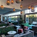 Interior del Botanical Lounge con sofás verdes y lámparas colgantes