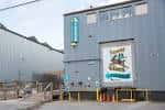 Fachada exterior del edificio de Jackalope Brewing Company con letrero vertical y mural del logo