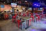 Interior del Redneck Riviera con mesas y sillas rojas bajo luces de neón