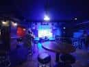 Escenario iluminado con luces azules y mesas de bar frente al mismo