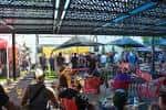 Área exterior cubierta con mesas, sombrillas y personas socializando