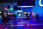 Interior del Super Rad Retro Lounge con máquinas arcade iluminadas y ambiente neón