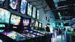 Vista amplia de la sala de juegos con múltiples consolas retro y luces vibrantes