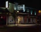Fachada nocturna del teatro ArtsWest en Seattle con letrero iluminado