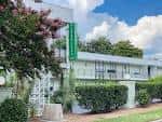 Fachada exterior del The Longleaf Hotel con estilo mid-century moderno y letrero verde