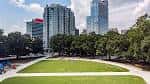 Amplia vista diurna de la zona verde central de Moore Square rodeada de árboles y rascacielos urbanos