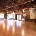 Salón principal con piso de madera pulida y vigas de techo expuestas