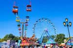 Rueda de la fortuna y cabinas colgantes en el parque de diversiones de la feria