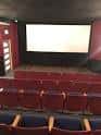 Interior del cine con butacas rojas y pantalla blanca