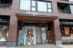 Fachada principal del Hugo House moderno con letrero visible y murales artísticos a los lados
