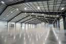 Interior de un pabellón vacío con techo metálico y suelo brillante