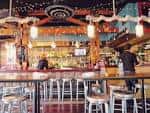 Interior del bar de Beer Kitchen con barra larga y luces colgantes
