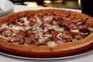 Pizza estilo Chicago con ingredientes visibles sobre mesa