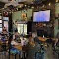 Interior acogedor de Tomorrow's Verse Taproom con mesas, clientes y pantalla de TV