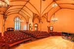 Interior del auditorio con butacas rojas y arco gótico