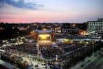 Vista panorámica del Red Hat Amphitheater al atardecer con el escenario iluminado y la multitud en las gradas
