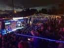 Vista nocturna del escenario al aire libre con público asistiendo a un concierto