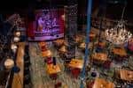 Vista interior del Cross-Eyed Critters Watering Hole con mesas y escenario iluminado