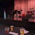 Escenario montado para evento musical con instrumentos y bebidas en primer plano