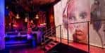 Interior del Aura Nightclub con iluminación de neón y una gran pantalla