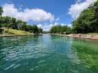 Agua cristalina del Barton Springs Pool con cielo azul