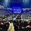 Interior del arena durante un evento con iluminación azul y pantalla central