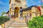 Estatua histórica frente a edificio colonial con escalinata decorada y vegetación tropical