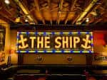 Escenario iluminado con letrero de neón 'The Ship'