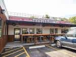 Fachada exterior del The Pit Room con mesas al aire libre