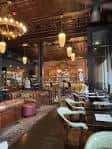 Interior acogedor de Tom's Town Distilling Co. con iluminación cálida y mesas dispuestas para eventos