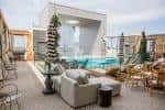 Zona de estar junto a la piscina con mobiliario moderno y decoración tropical