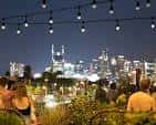Vista nocturna del Rooftop Bar con luces de cadena y skyline de Nashville al fondo