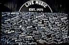 Pared interior decorada con firmas de artistas y el logo 'Live Music Est. 1971'
