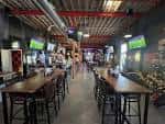 Interior del bar con barra larga, iluminación industrial y ambiente festivo