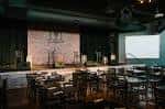 Configuración del salón para evento con escenario y disposición de mesas