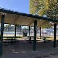 Área cubierta con mesas para picnic bajo un toldo en el parque