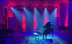 Escenario iluminado con luces de colores y piano en el centro