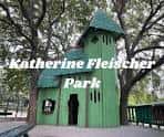 Pequeña casa verde de madera en Katherine Fleischer Park, rodeada de árboles