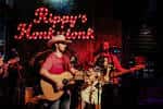Música en vivo en el interior de Rippy's Honky Tonk con banda tocando bajo luces rojas