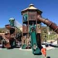 Área de juegos infantil con estructuras de madera y toboganes en Pioneer Park