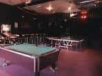 Sala de juegos con mesa de billar y mesas altas