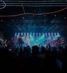 Concierto en vivo con banda en el escenario e iluminación de colores