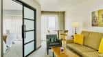 Interior de suite con sofá amarillo y puerta corredera de vidrio