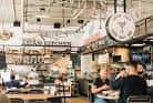 Área de comida en Little Italy Food Hall con letrero 'Asian Kitchen'