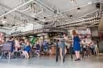 Espacio abierto en Little Italy Food Hall con personas caminando y sentadas