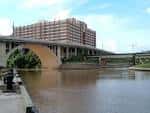 Paseo peatonal junto al río con bancos y vegetación en Allen's Landing Park