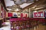 Sala de eventos con mesas y sillas rojas, decorada con techos ornamentados